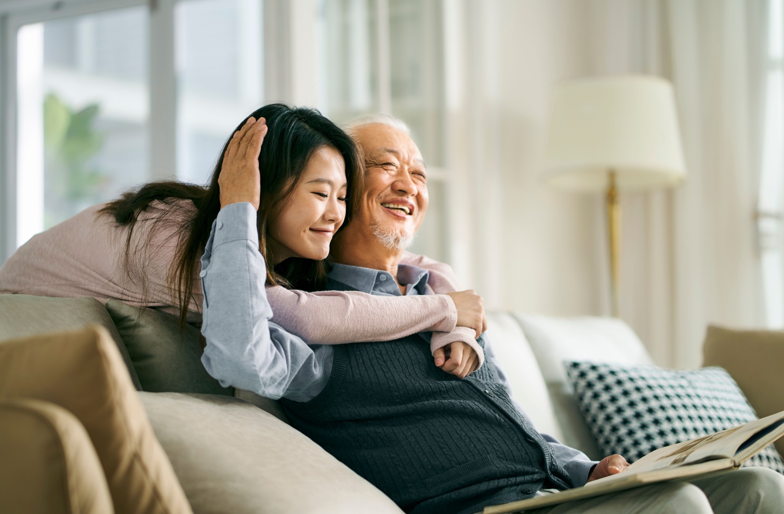 A happy young woman embraces her elderly father.