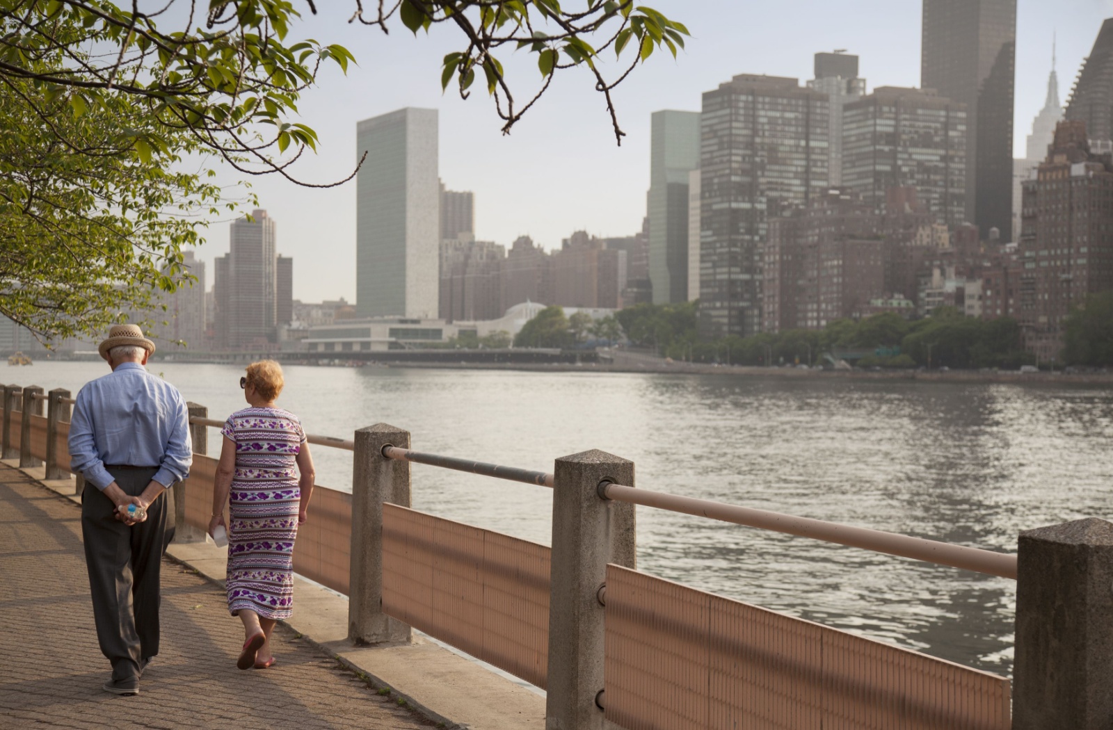 A senior couple walks along a river in New York.