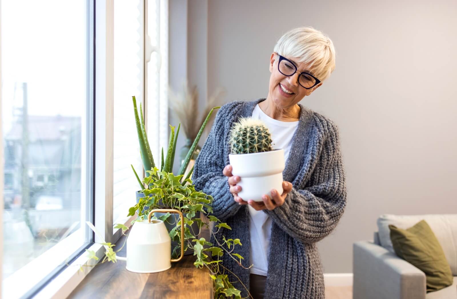 An older adult inspects their plants while decorating their room.