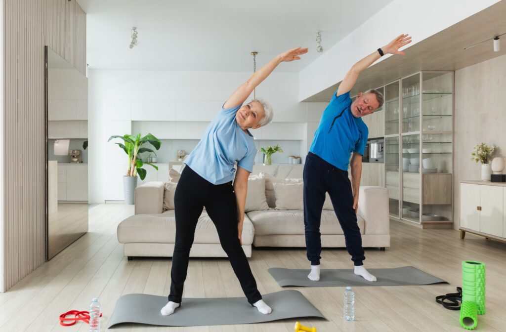 Older adults stretching on yoga mats in a bright modern living room with fitness gear nearby