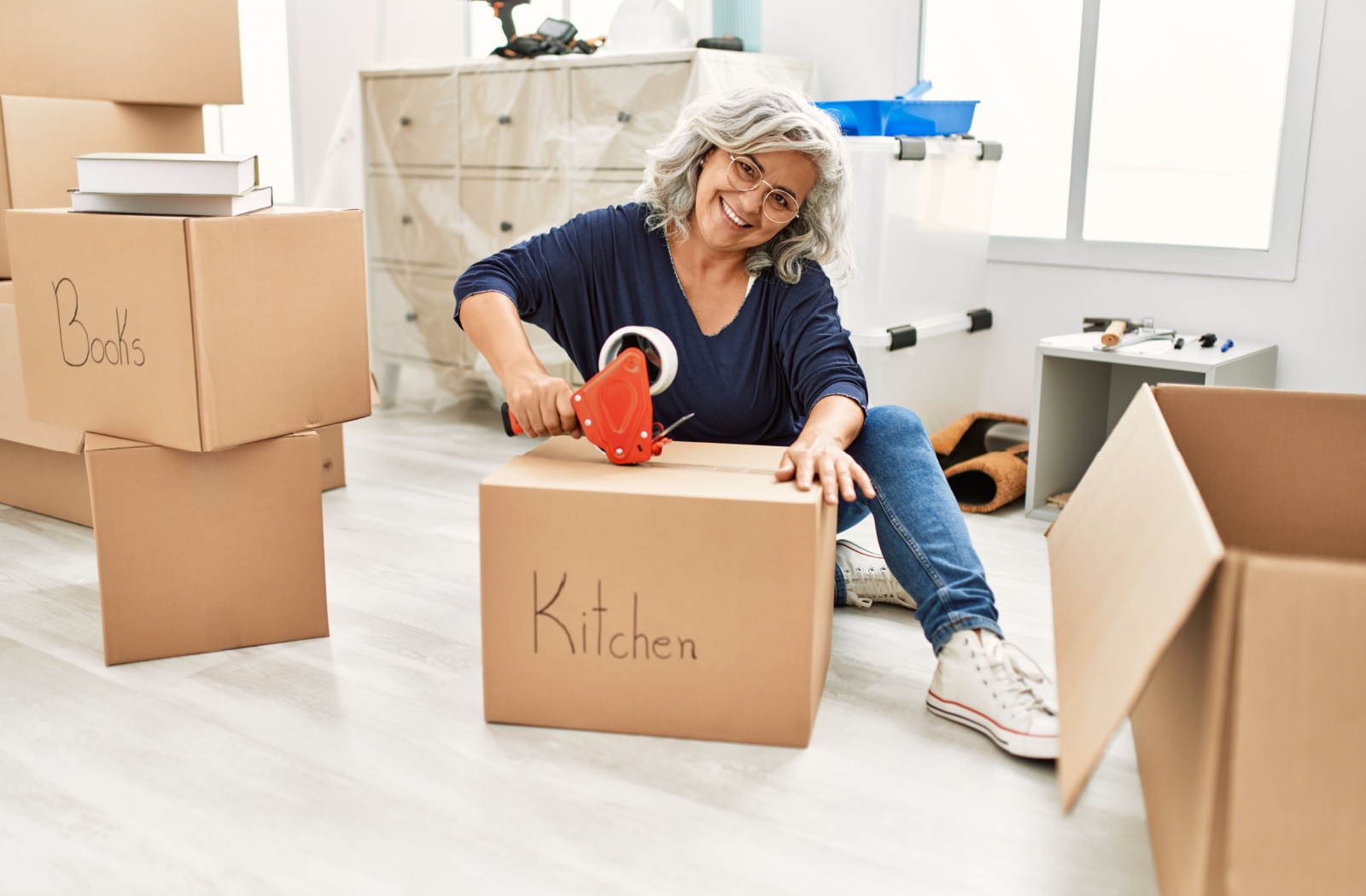 An older adult surrounded in boxes packs up their house to move to an assisted living community.