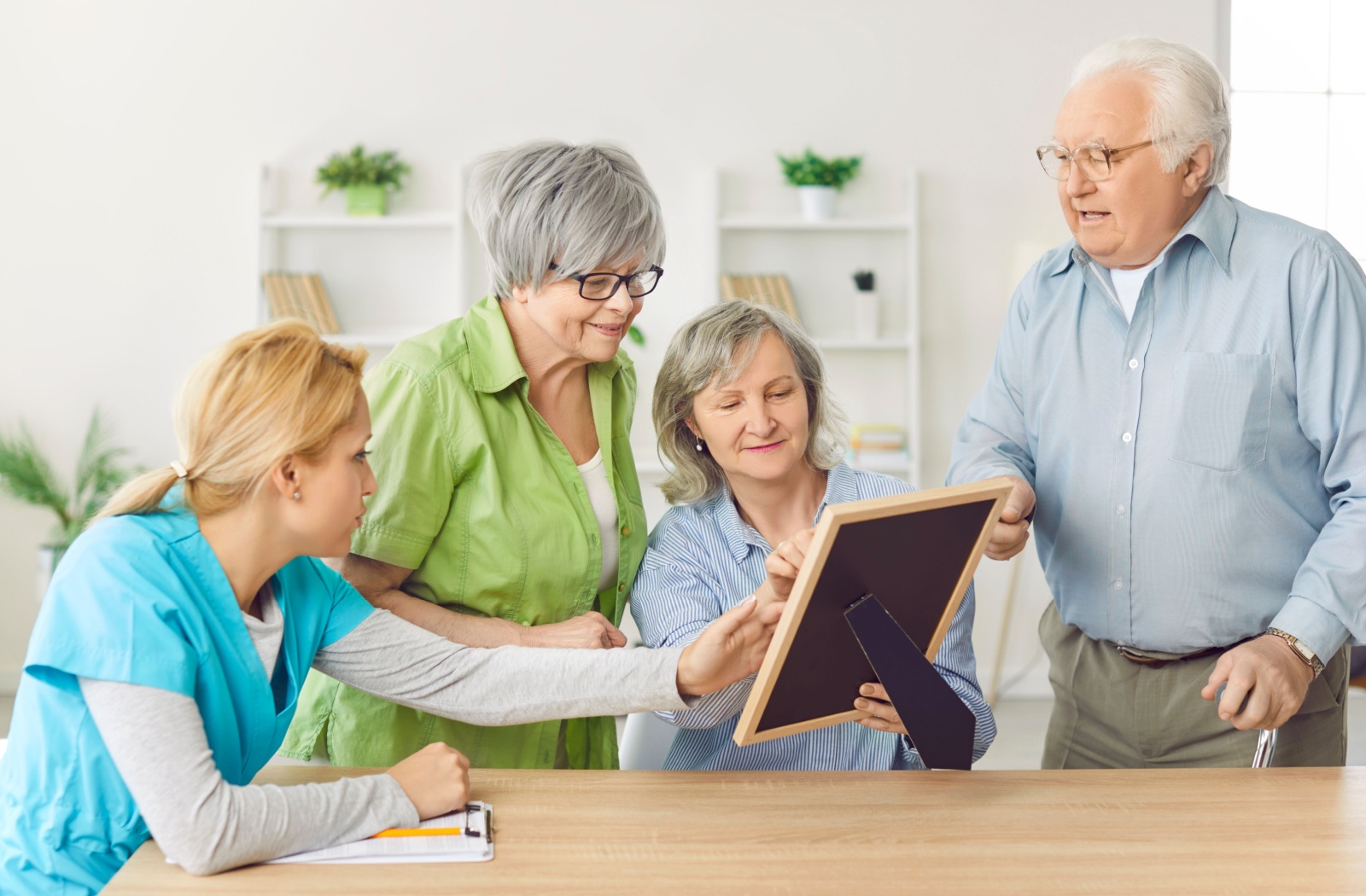 A caregiver helping 3 seniors look a photo and recollect some memories.