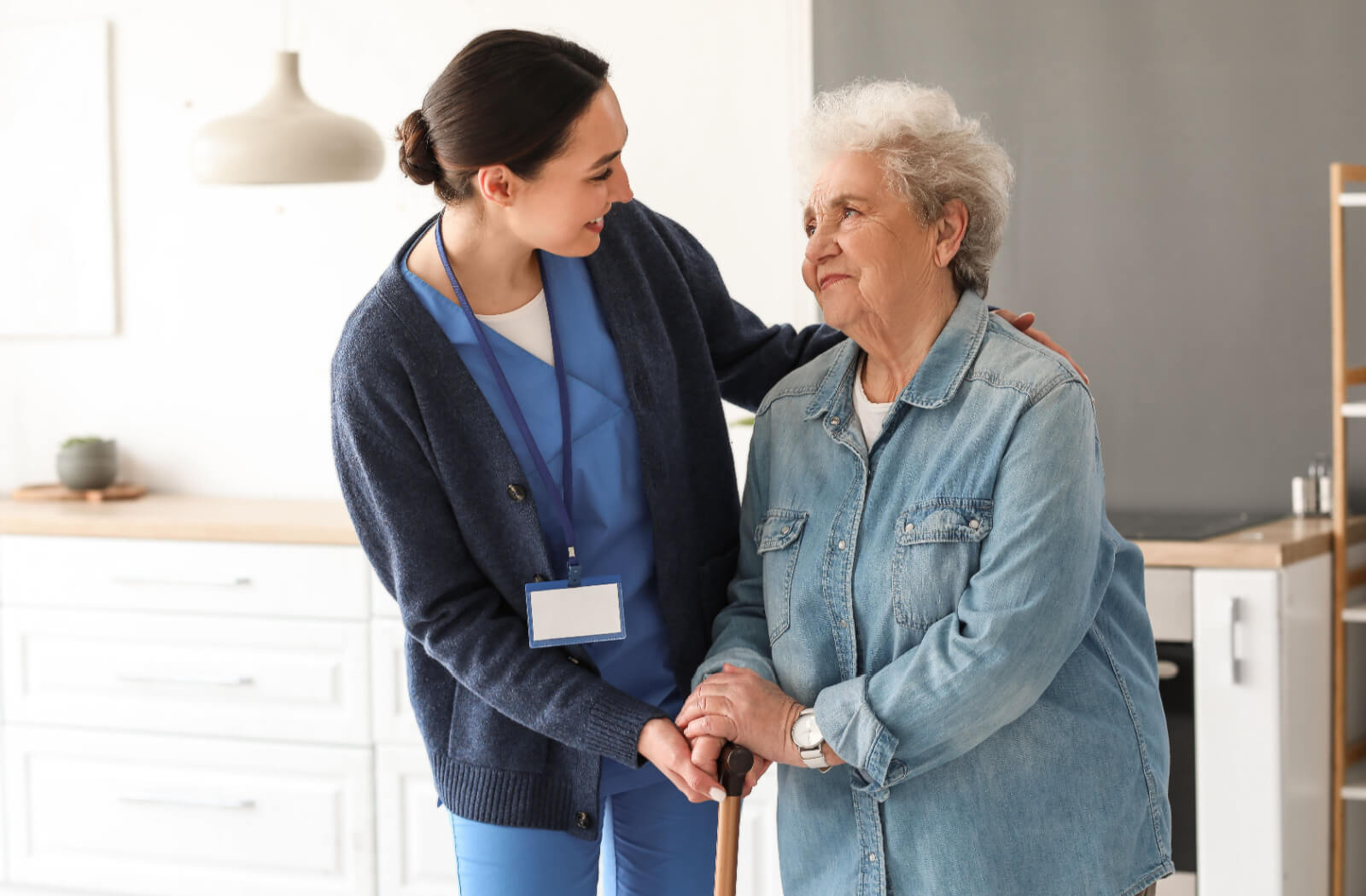 A caregiver smiles at an appreciative resident after handing them their cane to help them safely navigate their new community