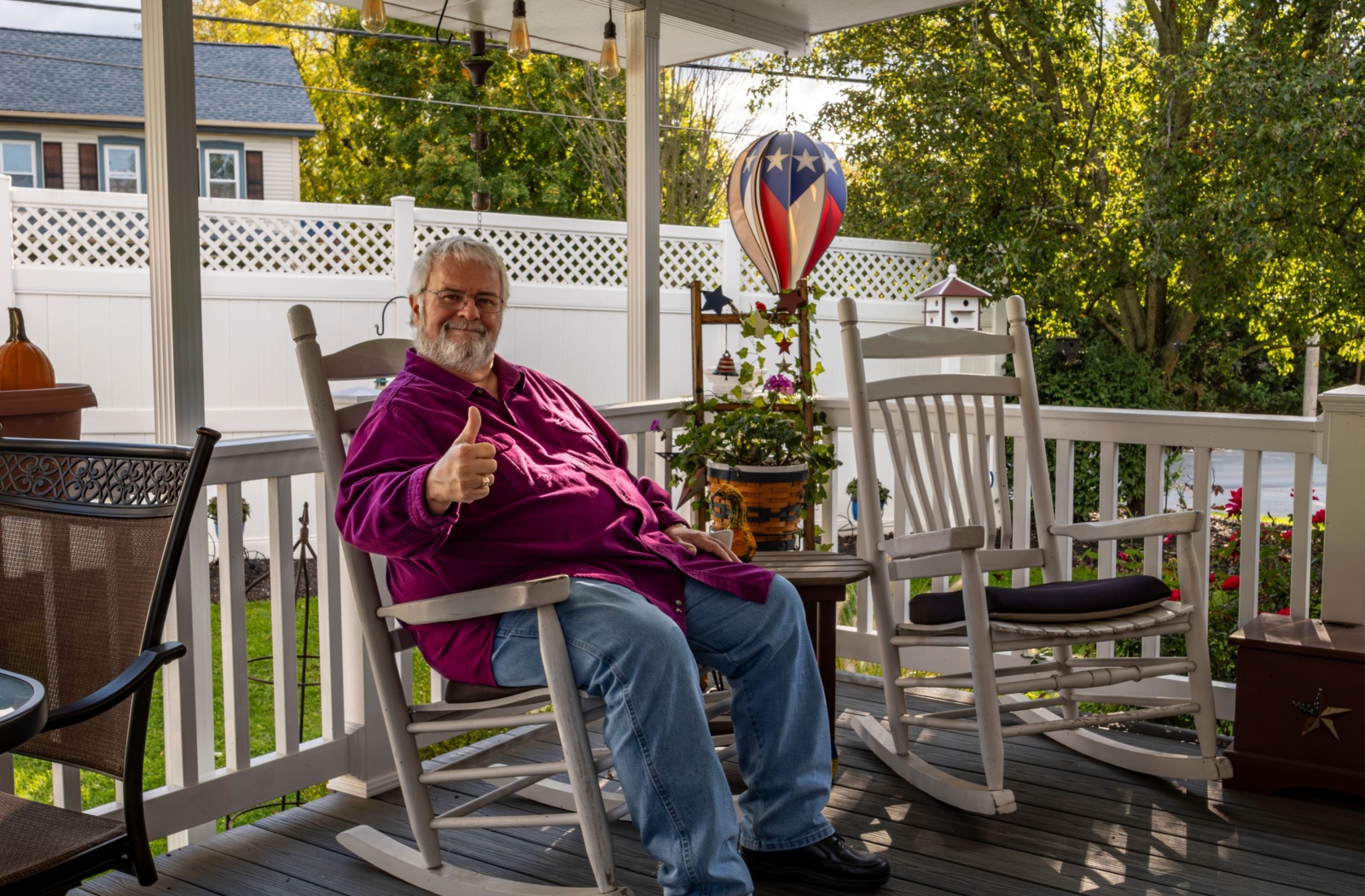 A senior sits on a rocking chair on the front porch of their assisted living community.